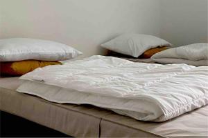 Una cama con sábanas blancas y almohadas. en Luxurious Appartment on Eilandje en Amberes