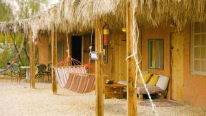 two hammocks in front of a house with a thatch roof at Tobiana Desert Lodging Negev in ‘Ezuz