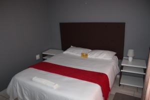 1 dormitorio con 1 cama con manta roja y blanca en ONESI Guest House en Maseru