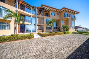 a large apartment building with a cobblestone driveway at Corona del Mar #6 in Ocotal