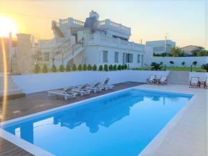a villa with a swimming pool in front of a house at The White House Beach Villa in Rafina