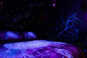 a dark room with a bed with purple lighting at Avataar - L'arbre de Pandoraa in Belfort