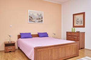 sypialnia z dużym łóżkiem z fioletowymi poduszkami w obiekcie Apartments Lovric with sea view w mieście Kaštela