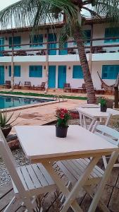 a table and chairs in front of a hotel with a pool at Vila Pura Vida in Canoa Quebrada