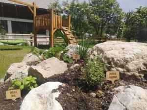 een tuin met rotsen en een speeltuin met een bank bij Alpine Joy Apartments in Bohinj