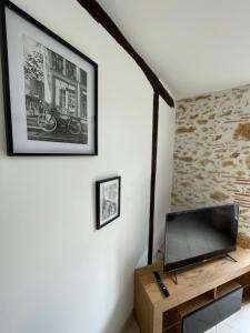 ein Wohnzimmer mit einem TV und einer Ziegelwand in der Unterkunft Le Pyrénéen - L'industriel - Maison Cosy in Cazaubon