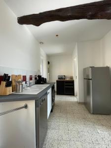 uma cozinha com um frigorífico de aço inoxidável num quarto em Le Pyrénéen - L'industriel - Maison Cosy em Cazaubon