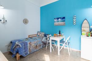 1 dormitorio con paredes azules, mesa y cama en SyracuseApartments IL PASUBIO di SIRACUSA Stupendo appartamento vicino ad ORTIGIA a 200m dal MARE, en Siracusa