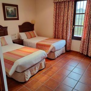 a room with two beds and a tile floor at Hotel Rural Carlos Astorga in Archidona
