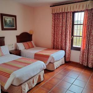 a hotel room with two beds and a window at Hotel Rural Carlos Astorga in Archidona