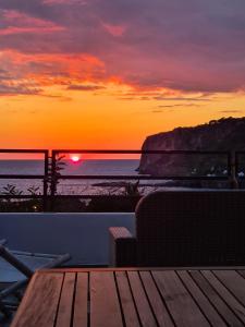 un tramonto sull'oceano con un tavolo in legno di La Casetta Bianca a Praia a Mare