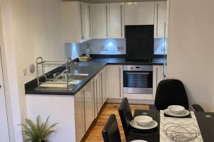 Superb Apartment CR0 في كرويدون: مطبخ مع حوض وطاولة مع كراسي