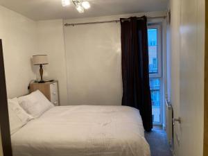 Superb Apartment CR0 في كرويدون: غرفة نوم بسرير ابيض ونافذة