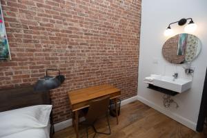 1 dormitorio con pared de ladrillo, mesa y lavamanos en The Flat NYC, en Nueva York