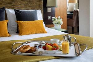 a breakfast tray with fruit and toast on a bed at The Cavendish London in London