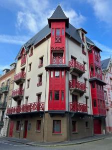 un gran edificio rojo y blanco con balcones rojos en Appartement le penthouse, Villa Les Bains De Mers en Mers-les-Bains