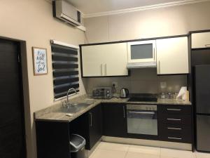 a kitchen with black and white cabinets and a sink at URBAN PARK UMHLANGA J001 in Durban