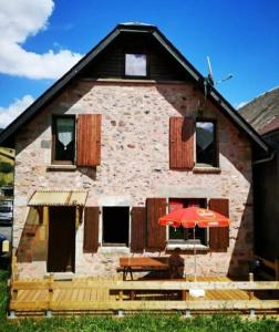 ein Haus mit einem Tisch und einem Sonnenschirm davor in der Unterkunft LA RUSTIQUE DU BOUT DU LAC in Chambon-sur-Lac