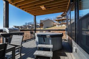 a deck with a trash can and chairs and a grill at Modern Rustic in Branson