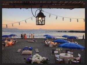 una spiaggia con tavoli, sedie e ombrelloni blu di Ercolano City Center a Ercolano