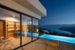a house with a view of the ocean at night at Green Tree Villas in Rabac