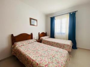 a bedroom with two beds and a window with blue curtains at Casa Inma Las Piteras. Sol y agua in Costa Teguise +37 photos