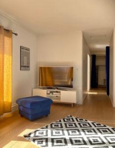 sala de estar con TV y otomana azul en Charmant Appartement Pop - Arty, en Thonon-les-Bains
