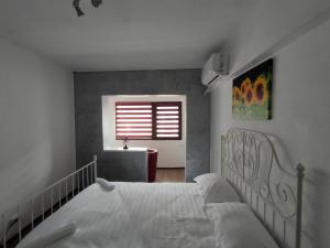 a bedroom with a white bed and a window at ANDI 3-apartament in Băile Herculane