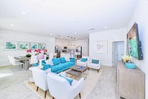 uma sala de estar com um sofá azul e cadeiras brancas em 12BR Family Home w Pool and Hot tub em Kissimmee