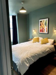 a bedroom with a large bed with two yellow pillows at Chic Townhouse near Tunnels Beaches Ilfracombe in Ilfracombe