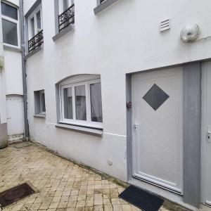 biały budynek z drzwiami i dwoma oknami w obiekcie La courée w mieście Boulogne-sur-Mer