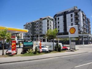una gasolinera con coches estacionados frente a un edificio en Apartamento com piscina 15 mim da Praia, en Cabo Frío