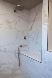 y baño con ducha y paredes de mármol blanco. en Alla Torre - nel cuore del Borgo storico en Castagnole Lanze