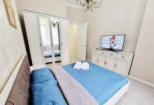 ein Schlafzimmer mit einem blauen Bett und einem TV in der Unterkunft Zaman in Atyrau