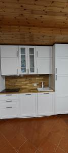 cocina con armarios blancos y techo de madera en La casetta di Diego, en Abetone