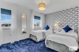 Duas camas num quarto com tapete azul em Silver Stag Properties, Spacious 3 Story House em Whitwick