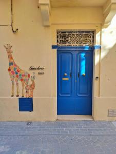 una puerta azul con una jirafa en el lateral de un edificio en Gawhra B&B en Victoria