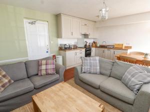 un salon avec deux canapés et une cuisine dans l'établissement Mellfell Cottage, à Watermillock
