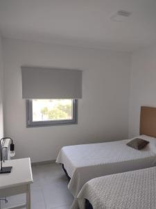 Habitación blanca con 2 camas y ventana en Al Mar - Torres del Este en Monte Hermoso