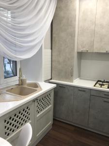 卡拉干達的住宿－Люкс в центре Караганды，厨房配有白色橱柜、水槽和窗户。
