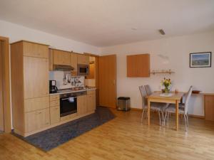 a kitchen with wooden cabinets and a table with chairs at Ferienwohnung am Maiglöckchenberg in Karlshagen