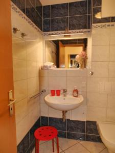 een badkamer met een wastafel en een rode kruk bij Ferienwohnung am Maiglöckchenberg in Ostseebad Karlshagen +10 foto's