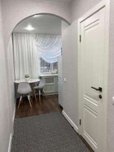 un couloir avec une table, une fenêtre et une porte dans l'établissement Люкс в центре Караганды, à Karaganda