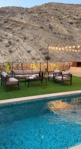 a pool with benches and a table next to a mountain at W muscat bay in Muscat