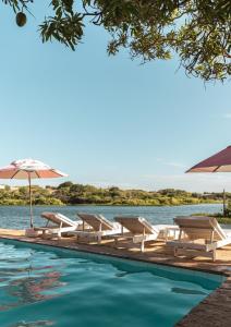 a pool with chairs and an umbrella and water at Casa na Lagoa in Paracuru