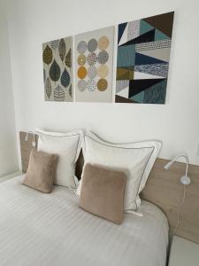a bed with two pillows and two paintings above it at Aix Homes "Les Allées Provençales" in Aix-en-Provence
