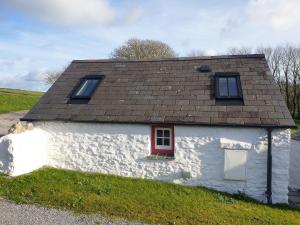 a white cottage with a red door and windows at The Old Dairy in Pembroke