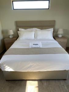 a bedroom with a large white bed with a window at Bluewave Farm Villa in Louis Trichardt
