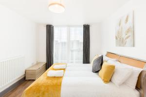 a white bedroom with a large bed with yellow pillows at Comfort Living Properties - Deluxe Apt, Birmingham City Centre in Birmingham