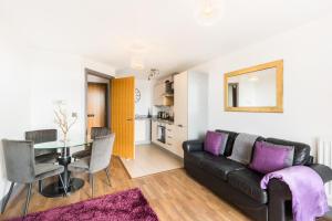 a living room with a black couch and a table at Comfort Living Properties - Deluxe Apt, Birmingham City Centre in Birmingham